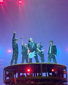 a group of men standing on top of a stage with their arms in the air