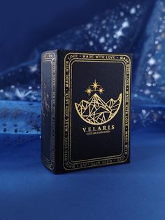 a black and gold playing card case on a blue surface with snowflakes in the background