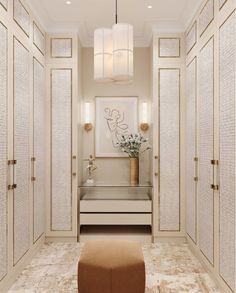 a white closet with gold trimmings and glass doors on the front, along with a footstool