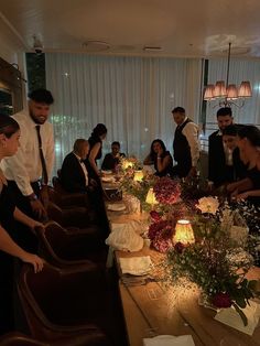 a group of people standing around a long table with flowers and candles on top of it