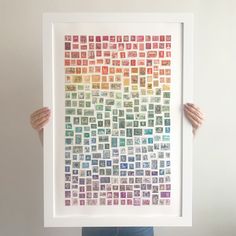 a person holding up a framed art print with stamps on it's sides and the words,