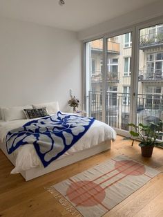 a bedroom with a large bed and wooden floors next to a window that looks out onto the city