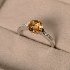 This ring features a 7mm round cut natural citrine and sterling silver finished with rhodium. Customization is available. It is made by hand, and it will take about 7 days to finish the ring after your payment is completed. Main stone: genuine citrine Citrine weight: Approx 1.40 ct Metal type: sterling silver finished with rhodium Accent stone: cz Customization is available, I also can make it with 14k solid gold (white or yellow or rose) and diamond accent stone, just feel free to contact me. A Formal Citrine Diamond Ring With Center Stone, Formal Citrine Rings With Brilliant Cut, Citrine Center Stone Topaz Ring, White Gold Rings With Brilliant Cut Yellow Sapphire, Yellow Diamond Promise Ring With Birthstone, Yellow Diamond Birthstone Promise Ring, Classic Yellow Sapphire Round Rings, Yellow Birthstone Diamond Promise Ring, Classic Crystal Ring With Birthstone In Round Cut