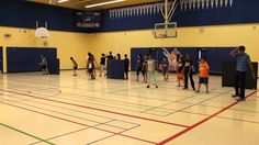 a group of people standing on top of a gym floor next to basketball hoops