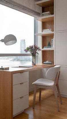 a white chair sitting in front of a wooden desk next to a window with a view