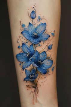 a blue flower tattoo on the side of a woman's leg with watercolors