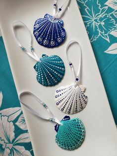 three seashell ornaments are sitting on a white platter with blue and green designs