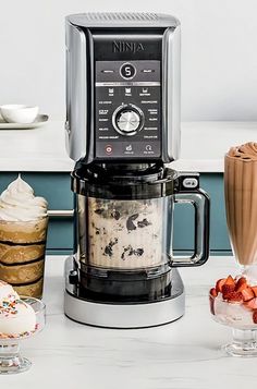 a coffee maker sitting on top of a counter next to ice cream and strawberries