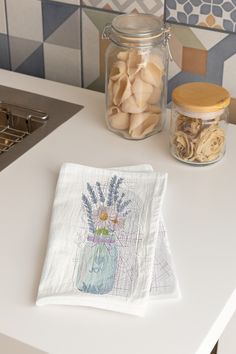 two napkins sitting on top of a counter next to a jar filled with nuts