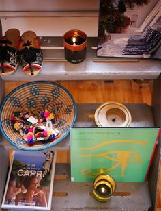 a shelf filled with shoes and other items on top of a wooden floor next to a candle