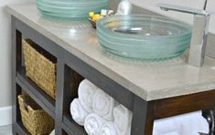 two glass bowls sitting on top of a bathroom vanity next to towels and soap dispensers