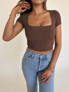 DETAILS: Our Holly Square Neck Crop Tee is a chocolate brown short sleeved crop top. This top features a chic square necklineand fitted silhouette with ruching on each side of the bodice. This top is completed with fine ribbing all throughout and is fully lined and has a very high quality feel This top is very versatile, fits true to size, and has stretch throughout. . This tee would be cute paired with ANY bottom! CONTENT & CARE: 92% Rayon. 8% Spandex. SIZE & FIT: Model is 5'5" The model is wea Ribbed Crop Top Outfits, Brown Crop Top Outfit, Brown Top Outfit, Espresso Aesthetic, Light Brown Top, Sleeved Crop Top, True Spring, Brown Crop Top, Casual Day Outfits