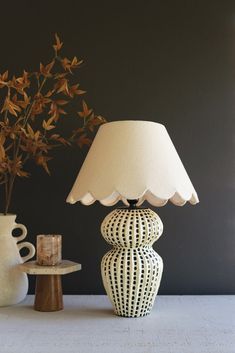 two vases sitting next to each other on a table with a lamp in front of them