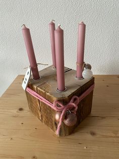 a wooden box with pink candles tied to it