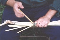 a man is holding several sticks in his hands