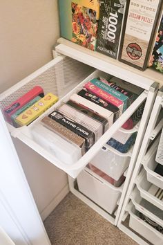 an organized pantry with white bins filled with books and other items on the shelves