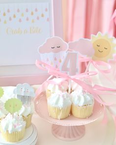 two cupcakes on a plate with pink ribbons and decorations in the shape of numbers