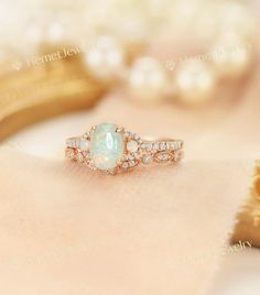 an opal and diamond ring sits on top of pearls