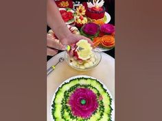 a person cutting into a cake on top of a table with flowers and candles around it