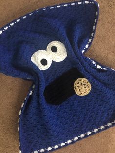 a blue crocheted hat with eyes and nose is laying on the floor next to a brown carpet