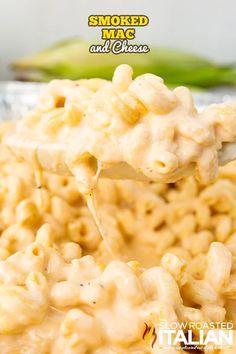 a spoon full of macaroni and cheese is being lifted from the bowl with a fork