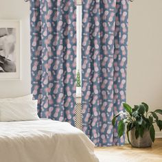 a bed room with a neatly made bed and a window covered in blue floral curtains