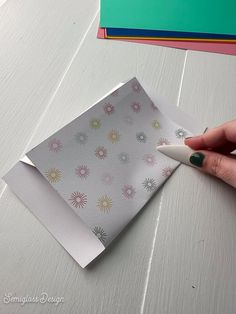 a hand holding a pen over a piece of paper on top of a table next to books