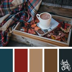 a cup of coffee on top of a tray filled with autumn leaves and plaid blankets