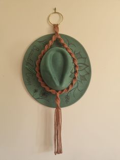 a green hat hanging on the wall with tassels around it's sides