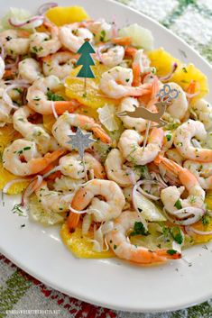 a white plate topped with shrimp and veggies next to a cut up christmas tree