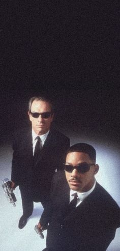 two men in suits and sunglasses standing next to each other