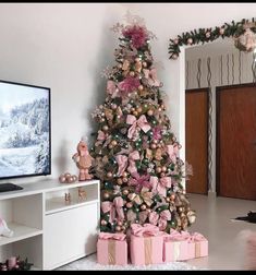 a decorated christmas tree with pink bows and ornaments in front of a flat screen tv