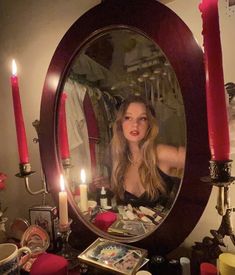 a woman is looking into a mirror with candles