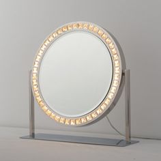 a round mirror sitting on top of a metal stand