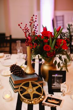 a table topped with books and vases filled with red flowers on top of it