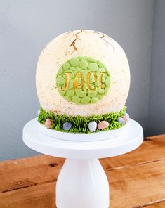 a cake with the word jac on it sitting on top of a white pedestal