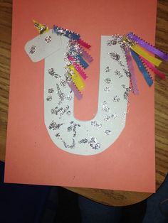 the letter u is made out of paper with glitters and unicorn ears on it