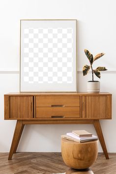 a wooden table with a plant on it and a white frame hanging above the table