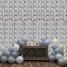 balloons are on the floor in front of a wall with silver and white balls hanging from it