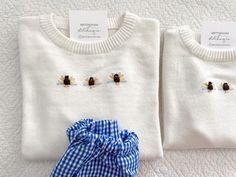 two white sweaters with blue checkered bows on them