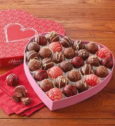 a heart shaped box filled with chocolates on top of a wooden table