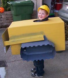 a young boy is dressed up as a construction worker with a cardboard box on his head