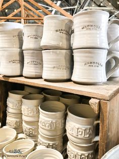 many white mugs stacked on top of each other in front of a wooden shelf