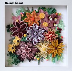 there are many flowers made out of felt in a frame on the wall or floor