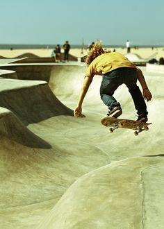 a skateboarder is in mid air doing a trick at a skate park while people watch