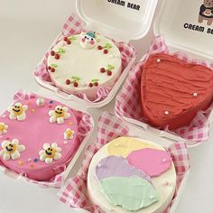 four decorated cakes in plastic containers on a table