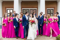 a group of people standing next to each other in front of a building with red and pink dresses