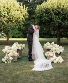 a bride and groom kissing in front of flower arrangements on the lawn at their wedding