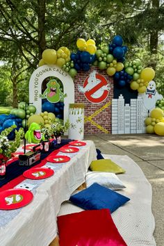 the table is set up for an outdoor party with balloons, plates and napkins