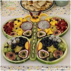 a butterfly shaped platter filled with fruit and crackers